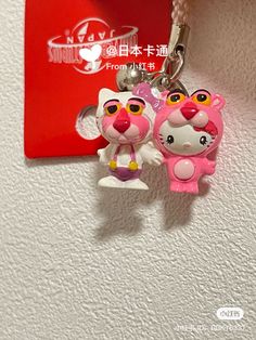 hello kitty keychain hanging on the wall next to a red tag with an image of two cats