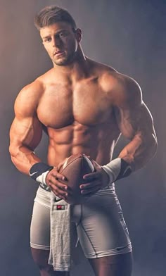 a shirtless man holding a football in his right hand and looking at the camera