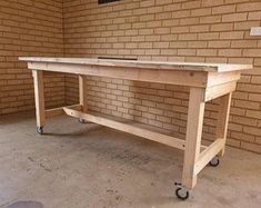 a wooden workbench sitting in front of a brick wall with wheels on it