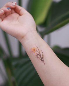 a woman's arm with a small flower tattoo on the left side of her wrist