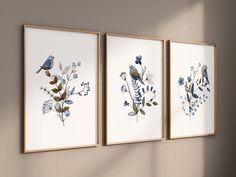 three framed art pieces with blue flowers and birds on them in front of a wall