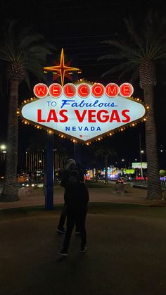 a man standing in front of the welcome sign to fabulous las vegas nevada at night