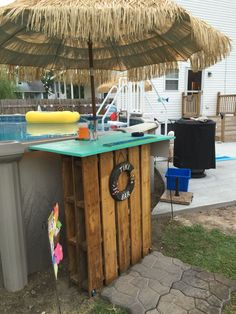 an outdoor bar made out of pallet wood with a green counter top and umbrella over it