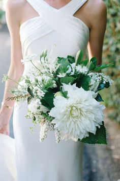 a bride holding a bouquet of white flowers