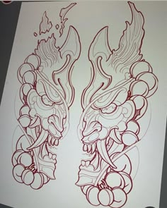 a drawing of two dragon heads with red ink on white paper, one is in the process of being drawn