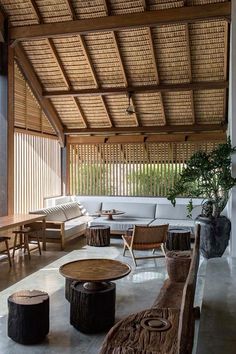 a living room filled with lots of furniture and wooden tables on top of cement flooring