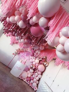 balloons and streamers are hanging from the ceiling in a room with pink decorations on it