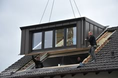 two men are working on the roof of a house that's being built with metal shingles