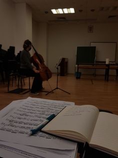 an open book sitting on top of a table next to music sheets and musical instruments