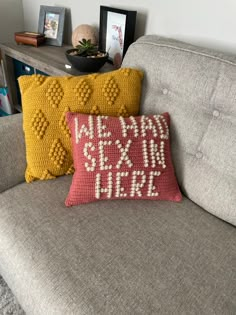 two pillows are sitting on a couch in front of a shelf with books and pictures