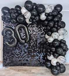 black and white balloons are arranged in the shape of an o on a mosaic wall