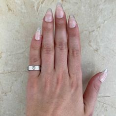 a woman's hand with white nails and a ring on her left hand, against a marble background