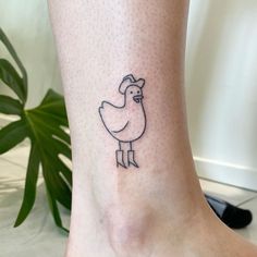 a small tattoo on the ankle of a woman's foot with a chicken drawn on it