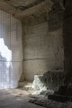 an empty room with stone steps and tiled walls in the background, light coming through