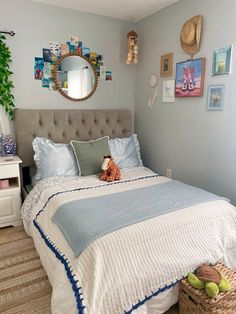 a bedroom with blue and white bedding, pictures on the wall and a teddy bear