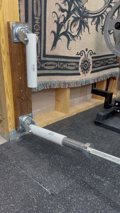 a large metal pipe is attached to the floor in front of a rug on display