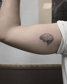 a man's arm with a small brain tattoo on it