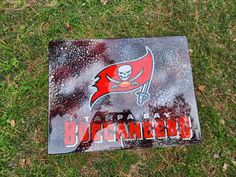 a sign that is laying on the ground in the grass with a football logo painted on it