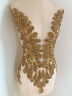 the back of a mannequin with gold sequins and leaves on it