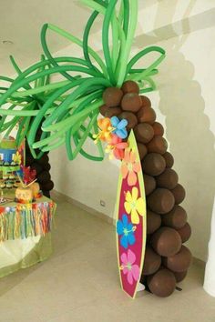 a surfboard decorated with flowers and palm trees is in front of a balloon sculpture