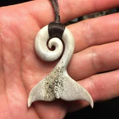 a hand holding a white and brown pendant