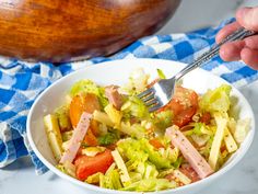 a white bowl filled with salad on top of a blue and white checkered table cloth