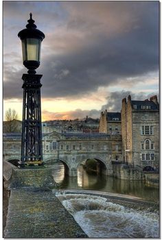 a street light sitting next to a river under a cloudy sky