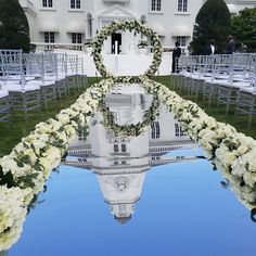 an outdoor ceremony with white flowers and greenery in front of a large building on the lawn