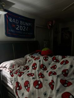 there is a bed with spiderman sheets on it and a sign above the bed