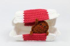 a small crocheted teddy bear in a red and white box