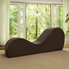 a black chaise lounger sitting in front of a large window with trees outside