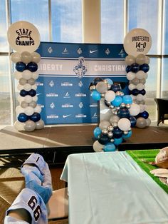 an arch made out of balloons and football jerseys is displayed in front of a large window