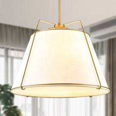 a light fixture hanging from the ceiling in a living room with a large window behind it