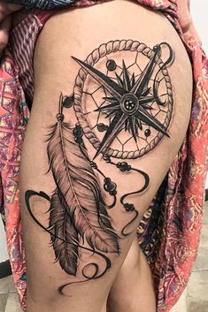 a woman's thigh with a tattoo on it that has a compass and a feather