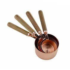 a set of five copper measuring cups with spoons in them on a white background