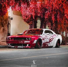 a red and white car parked in front of some trees