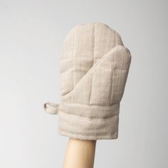 a hand with a beige oven mitt on it's head and the mitt is made out of fabric