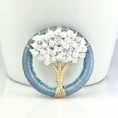 a blue and white brooch sitting on top of a coffee cup with flowers in it