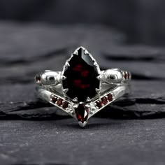 a close up of a ring with a garnetia stone in the center on a black surface