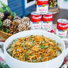 a large white bowl filled with food next to cans of campbell's soup and pine cones