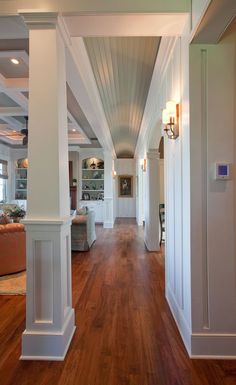 a long hallway with white columns and wood floors in an open concept living room area