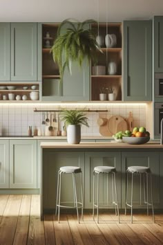 a kitchen filled with lots of green cabinets and counter top space next to a potted plant