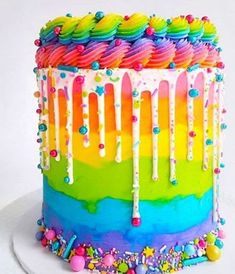 a multicolored rainbow cake with sprinkles and icing on top