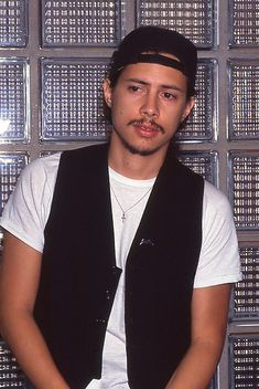 a young man wearing a black vest and hat