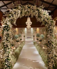 an aisle decorated with white flowers and greenery