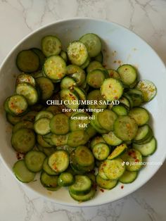 a white bowl filled with sliced cucumbers on top of a marble countertop