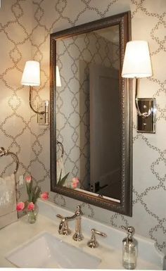 a bathroom sink sitting under a mirror next to a wall mounted faucet with two lights on it