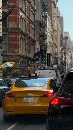 several cars are stopped at an intersection on a busy city street with tall buildings in the background