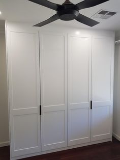 a ceiling fan is mounted to the side of a white closet with doors and drawers