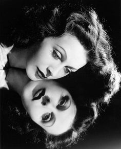 two women are posing for the camera with their eyes closed and one has her face painted black